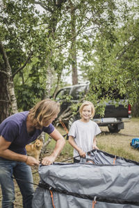 Father and daughter talking while pitching tent at camping site