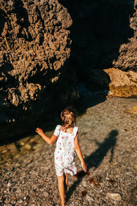 Full length of young woman standing on rock