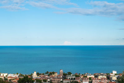 Aerial view of townscape by sea against sky