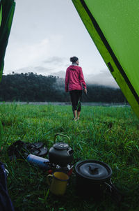 Rear view of woman walking on grass seen though tent in forest