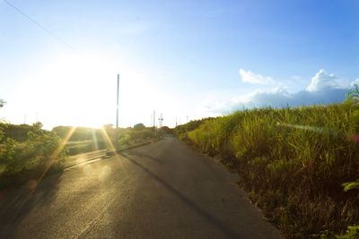 Road amidst field against sky