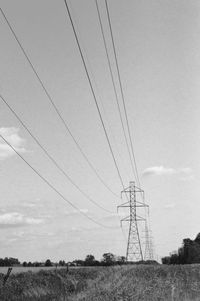 Low angle view of electricity pylon on field against sky