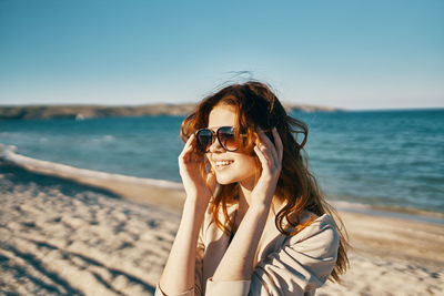 Portrait of woman with arms raised on beach