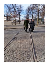 Rear view of people walking on sidewalk in city