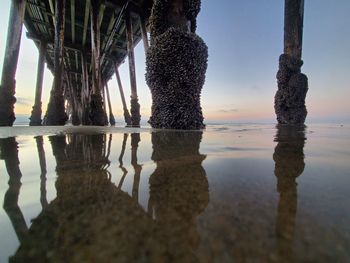 Reflection of pier on water against clear sky