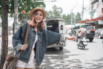 Portrait of smiling young woman standing on street in city