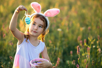 Portrait of young woman holding flowers on field