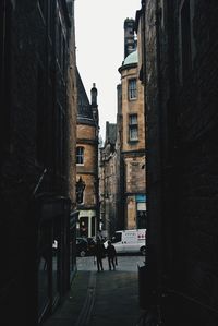 Rear view of people walking on road amidst buildings