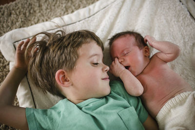 High angle view of brother lying by sister sleeping on bed at home