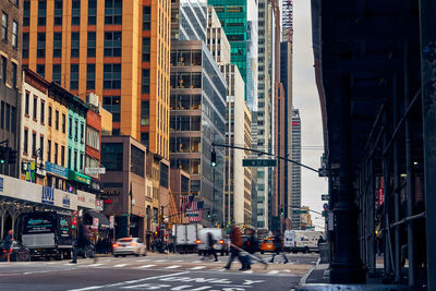 Street amidst buildings and people crossing in city of manhattan