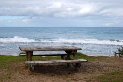 Chairs and table on beach against sky