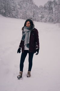 Portrait of young woman standing on snow covered land