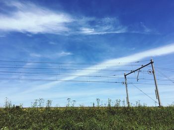 Low angle view of electricity pylon on field against sky