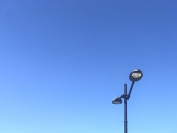 Low angle view of street light against blue sky