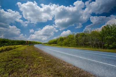 Road by trees against sky