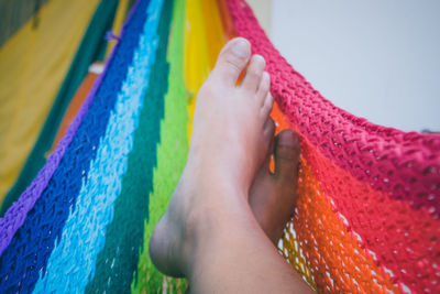 Low section of person relaxing on colorful hammock