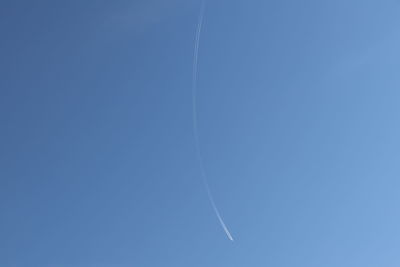 Low angle view of vapor trail against clear blue sky