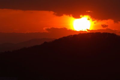 Scenic view of silhouette mountains against orange sky