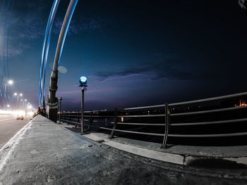 Illuminated street light against sky at night