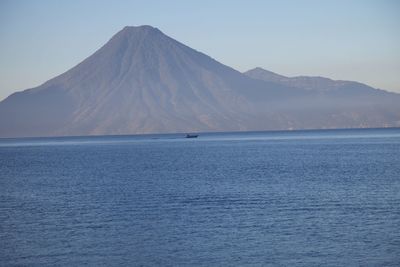 Scenic view of sea and mountains against clear blue sky