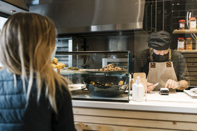 Rear view of woman standing in kitchen