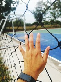 Midsection of person by swimming pool against fence