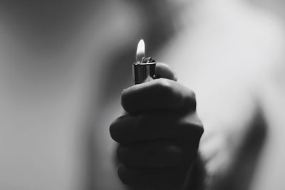 Cropped hand of person igniting cigarette lighter