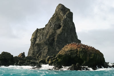 Rock formation on sea shore against sky