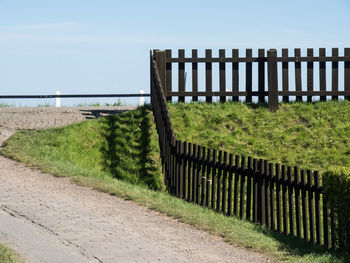 Fence on footpath by sea against clear sky