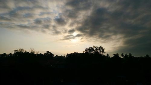 Silhouette of trees against cloudy sky