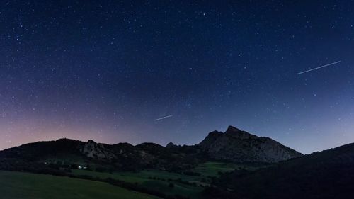 Scenic view of mountains against starry sky at night