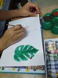 High angle view of hand holding paper at table