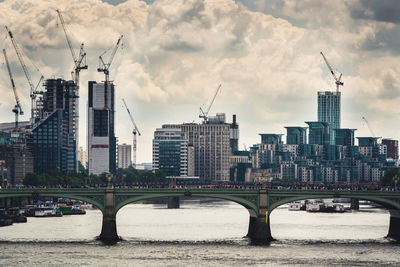 Southwark bridge over thames river against cloudy sky