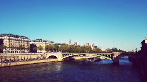 Bridge over river against blue sky in city