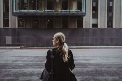 Rear view of businesswoman looking away in city