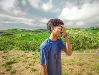 Young man standing on land against sky