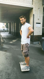 Portrait of man with skateboard standing in front of building