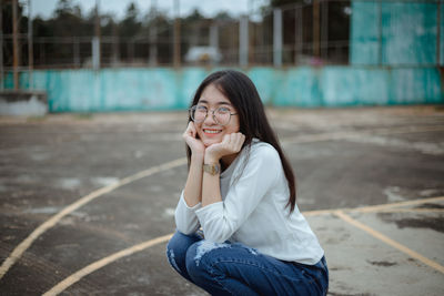 Smiling woman crouching at tennis court