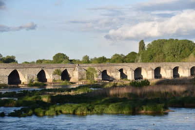 Arch bridge over river against sky