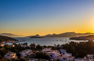 Scenic view of sea and buildings against sky during sunset