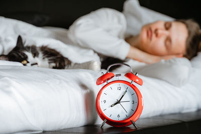 Young millennial candid woman sleeping with pet cat on white blanket bed cozy at home in bedroom.