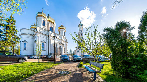 Cars on road amidst trees and buildings against sky