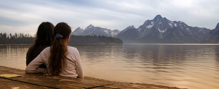 Rear view of woman looking at lake against mountains