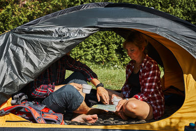 Couple planning next trip while sitting with map in tent. people relaxing in tent. camp life