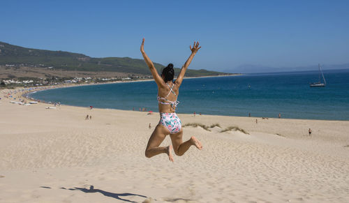 Happy young woman in swimsuit jumping at sand beach. relaxing, fun, and enjoy holiday at paradise