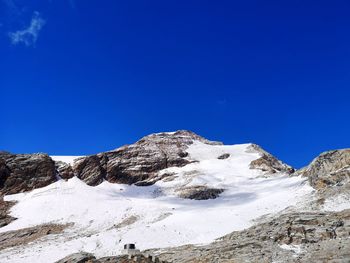 Low angle view of snowcapped mountains against clear blue sky