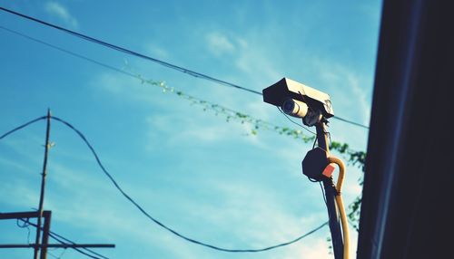 Low angle view of a security camera against sky