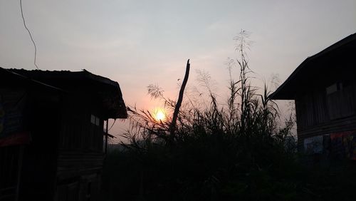 Silhouette houses against sky at sunset