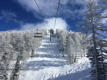 Ski lift over snow covered mountains against sky