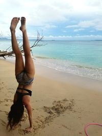 Low section of person on beach against sky